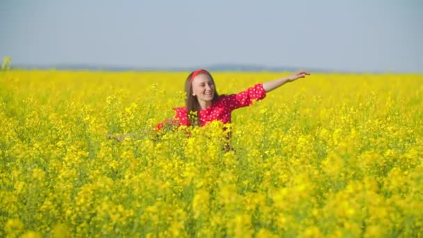 Flicka går över fältet med raps blommor — Stockvideo