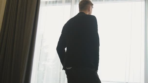 Хлопець стоїть біля вікна — стокове відео
