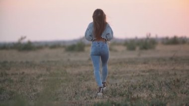 Doğada yürüyen kot elbiseli bir kız.