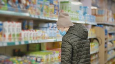 Tıbbi maskeli kadın ürünleri seçiyor.