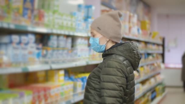 Vrouw met medisch masker kiest producten — Stockvideo
