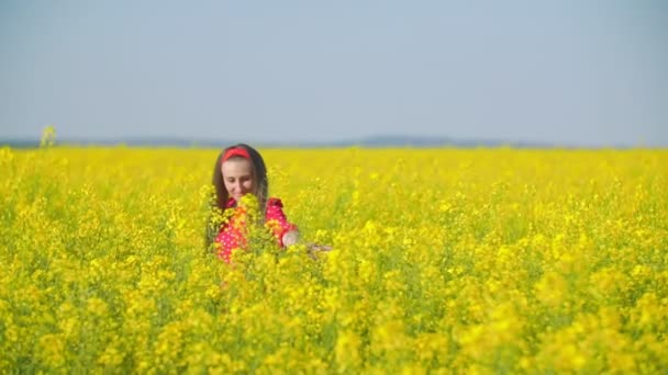 Mädchen läuft mit Rapsblüten über das Feld — Stockvideo