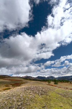 Karla kaplı dağ zirveleri ile manzara. Üzerinde bulutlar