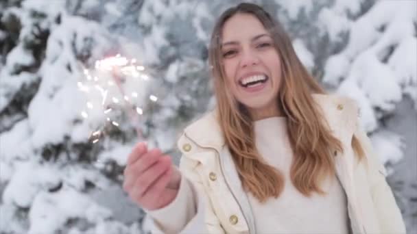 Pozitív kislány behavazott téli erdőben. Karácsonyi és csillagszórók — Stock videók