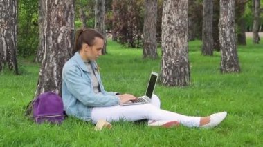 Genç güzel iş kadın kullanarak dizüstü bilgisayar üzerinde açık havada oturma