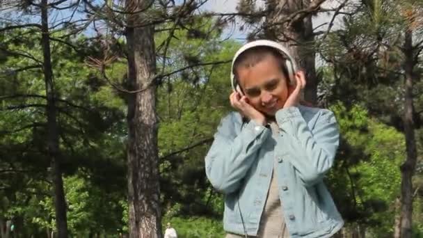 Красива дівчина з навушниками слухати музику і танцювати — стокове відео
