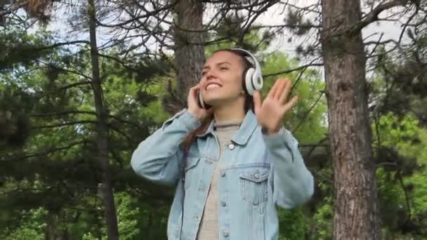 Joven linda chica en auriculares escuchando música en el teléfono móvil — Vídeos de Stock