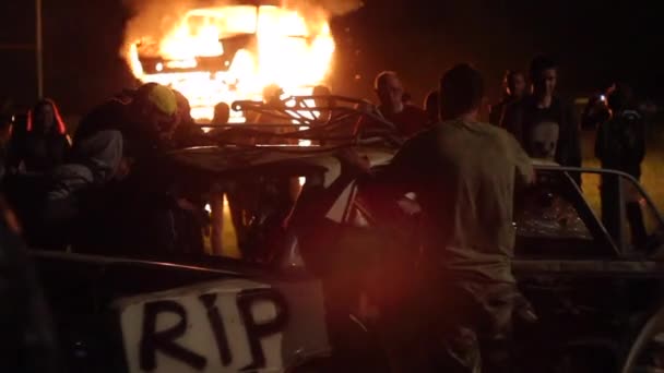 Los disturbios en la ciudad, fuego. La gente rompe el coche — Vídeo de stock