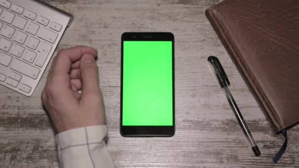 Smartphone con schermo verde isolato su tavolo di legno, vista dall'alto — Video Stock