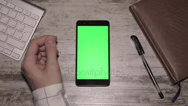 Smartphone met geïsoleerde groen scherm op houten tafel, bovenaanzicht — Stockvideo