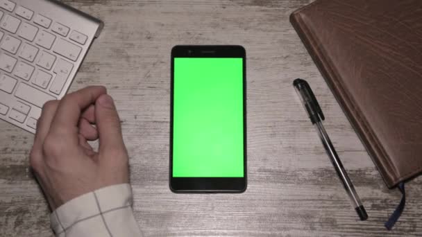 Hombre mano usando Smartphone en escritorio pantalla verde — Vídeos de Stock