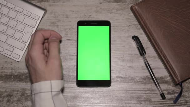 Mano dell'uomo utilizzando Smartphone sullo schermo verde scrivania — Video Stock