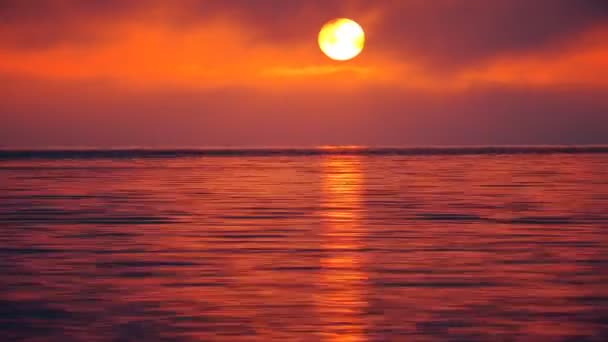 Zaman atlamalı. Gün batımı. Kızıl gökyüzünün ve denizin üzerinde güneş. — Stok video