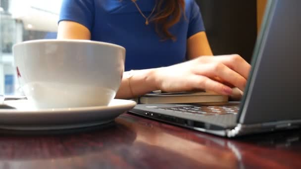 在一家咖啡馆的女人。还有一台笔记本电脑和桌上的咖啡. — 图库视频影像