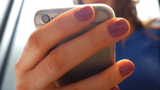 Une femme avec un téléphone portable près de la fenêtre . — Video