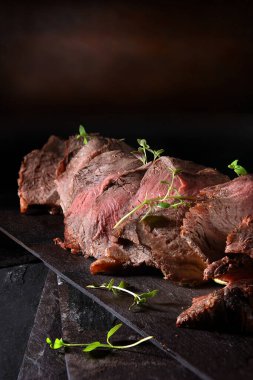 Dilimlenmiş az pişmiş biftek ve kekik garnitürlü koyu kırsal bir arka plan. Kopya alanı için cömert konaklama.