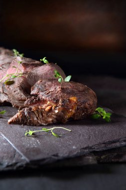 Dilimlenmiş az pişmiş biftek ve kekik garnitürlü koyu kırsal bir arka plan. Kopya alanı için cömert konaklama.
