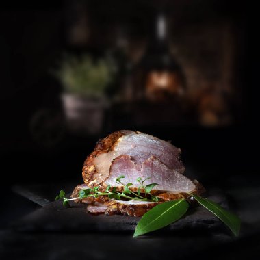 Kızarmış jambon, kekik ve defne yapraklı garnitürle servis edilmeye hazır. Kopyalama alanı için konaklama olanağı olan rustik bir arkaplana karşı çekim.