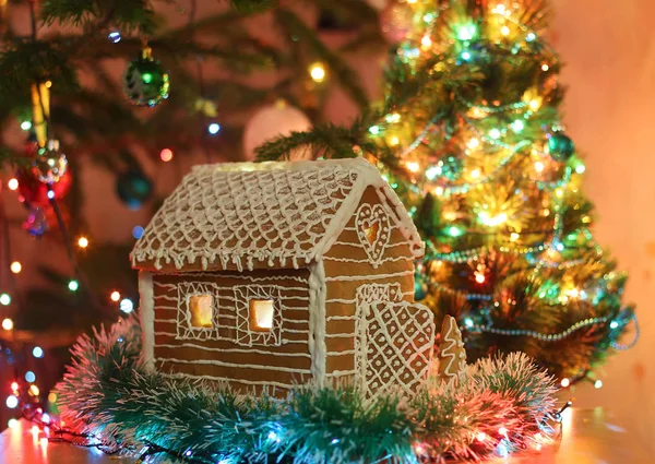Casa de gengibre com cobertura. Árvore festiva com luzes e guirlandas . — Fotografia de Stock