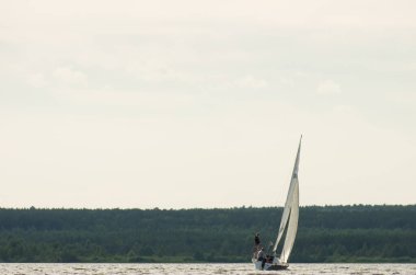 Yat nehirde gidiyor. Beyaz yat, yaz güneşi altında yüzüyor.
