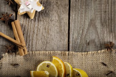 Tarçın çubukları, karanfil, kurabiye, limon ve portakal dilimli eski ahşap arka plan. Kır evindeki yemek çerçevesi ve mesaj için boş bir yer. Boşluğu kopyala.