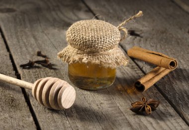 Kavanoz dekoratifi içinde ballı jüt malzemesi, anason yıldızı ve eski ahşap üzerinde bal kapanı..