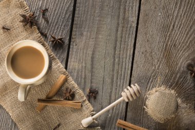 İçinde tarçın çubuğu, anasonlu yıldız, bal ve dipper olan jüt malzemeli bir fincan kahve. Kopyalama alanı olan eski arkaplan.