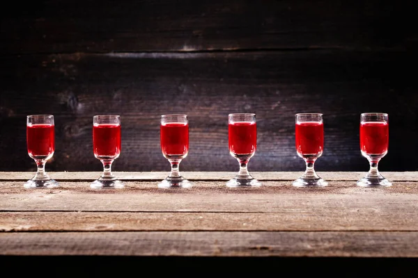 一套含酒精的樱桃鸡尾酒放在老式木制木板上的玻璃杯里 枪击案中伏特加酒的乡村背景 — 图库照片