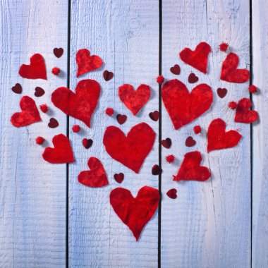 Tekstil kalplerinden yapılmış kırmızı kalp şekli ve ahşap turkuaz renk arka planda parlak elementler. Sevgililer Günü kavramı.