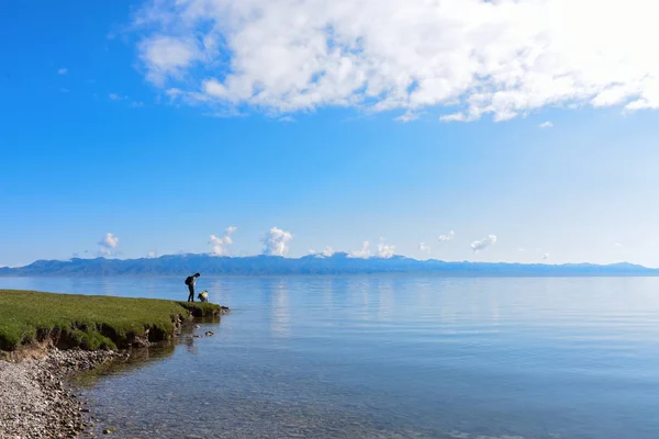 Homem e menina ao lado do lago Sayram no céu azul . — Fotografia de Stock