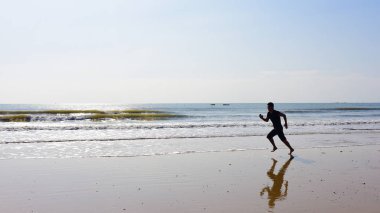 Çıplak ayakları adam plaj dalgalar ve yansıma ile çalışan. 