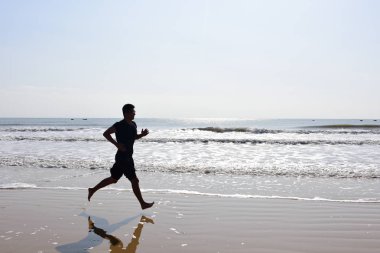 Çıplak ayak adam silüeti plaj dalgalar ile çalışan