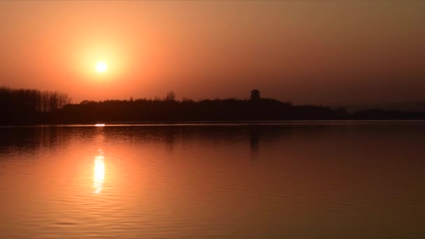 Spokojne jezioro z fale i chińskim budynku w ciepłym świetle przed zachodem słońca — Wideo stockowe