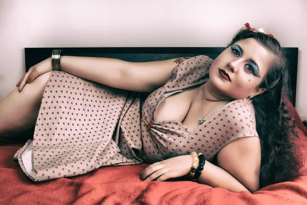 Pinup flicka poserar på en röd säng — Stockfoto