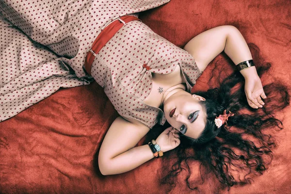 Девушка в пинапе позирует на красной кровати — стоковое фото