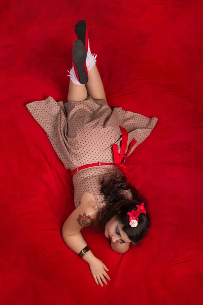 Девушка в пинапе позирует на красной кровати — стоковое фото