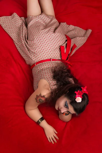 Pinup menina posando em uma cama vermelha — Fotografia de Stock