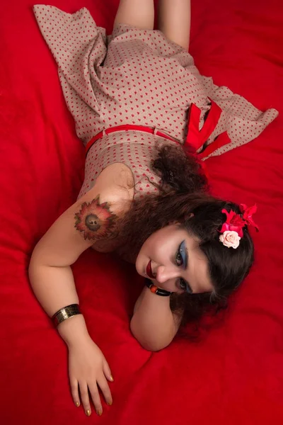 Pinup κορίτσι θέτοντας σε ένα κόκκινο κρεβάτι — Φωτογραφία Αρχείου
