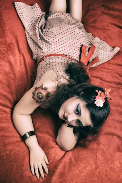 Pinup menina posando em uma cama vermelha — Fotografia de Stock