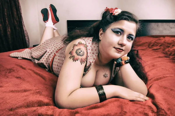 Pinup ragazza in posa su un letto rosso — Foto Stock