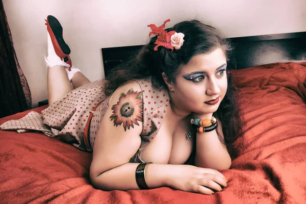 Pinup ragazza in posa su un letto rosso — Foto Stock