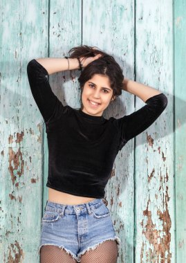 Yeşil ahşap arka plan üzerinde kısa mavi jeans ile güzel bir genç kadının Görünümü Kapat.