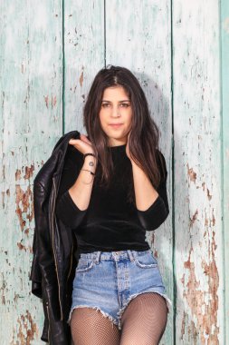 Yeşil ahşap arka plan üzerinde kısa mavi jeans ile güzel bir genç kadının Görünümü Kapat.