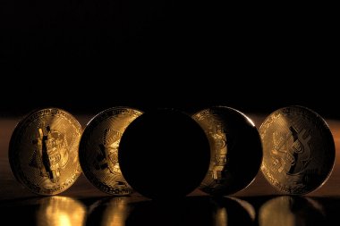 Ahşap masa üstünde parlak altın bitcoins gölgeler görünümünde.