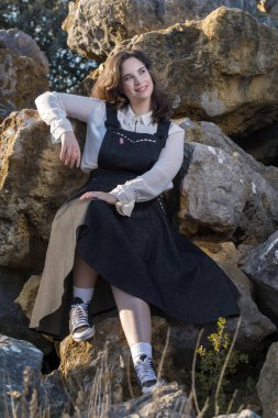 Vintage giyim ile doğada kaya üzerine poz kız.