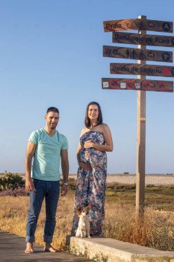 Küçük köpeği olan mutlu hamile çift.