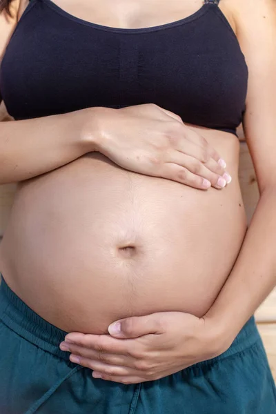 Schwangere posiert mit Händen am Bauch — Stockfoto