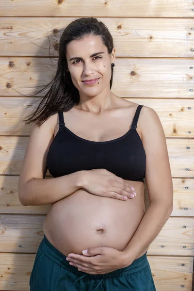 Pregnant woman poses with hands on belly — Stock Photo, Image