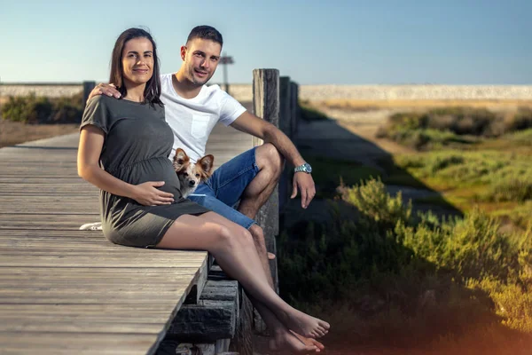 Embarazada feliz pareja con pequeño perro —  Fotos de Stock