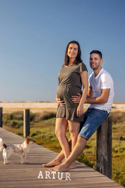 Küçük köpeği olan mutlu hamile çift.